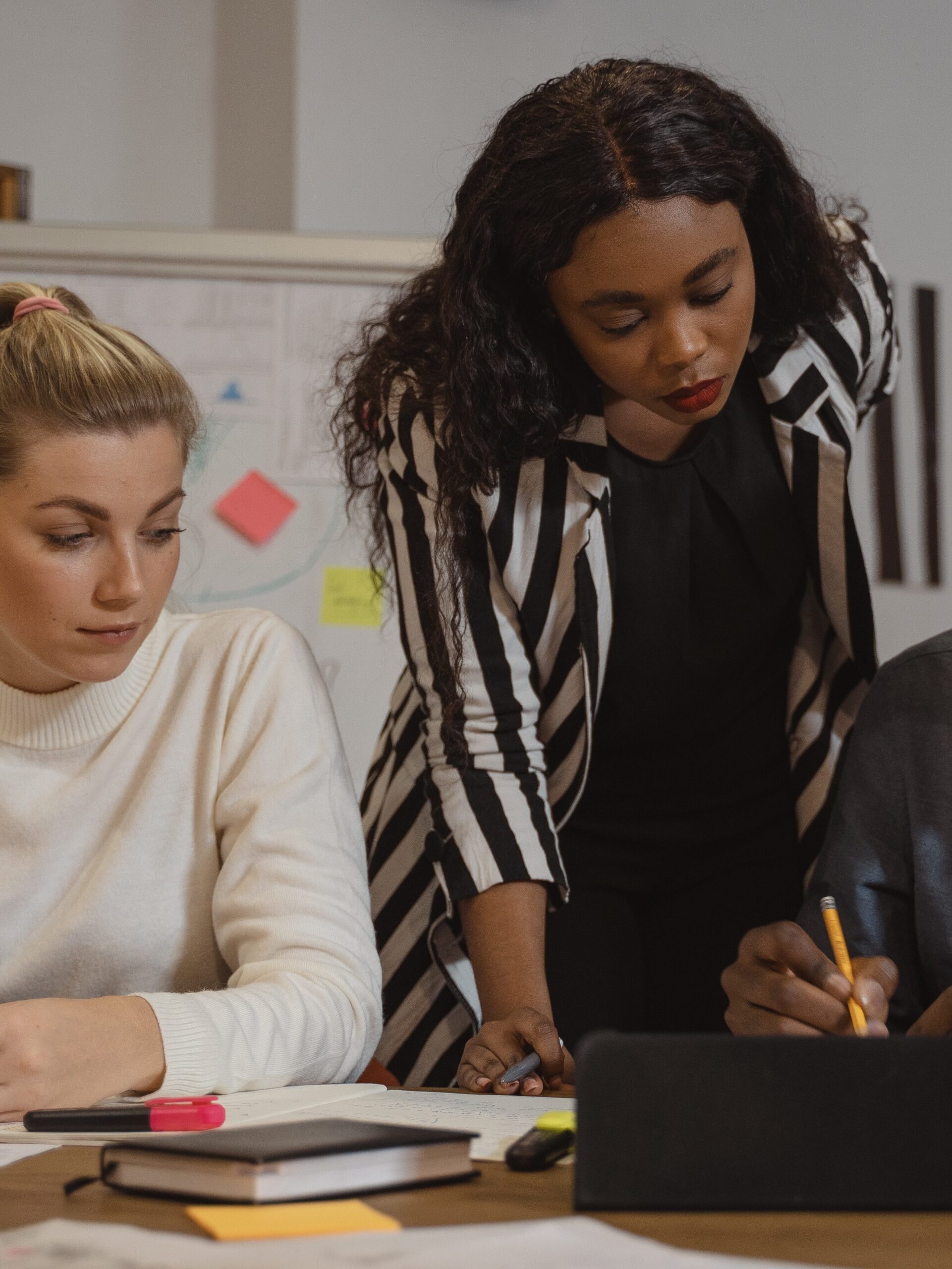 Three teachers discussing course material at a desk